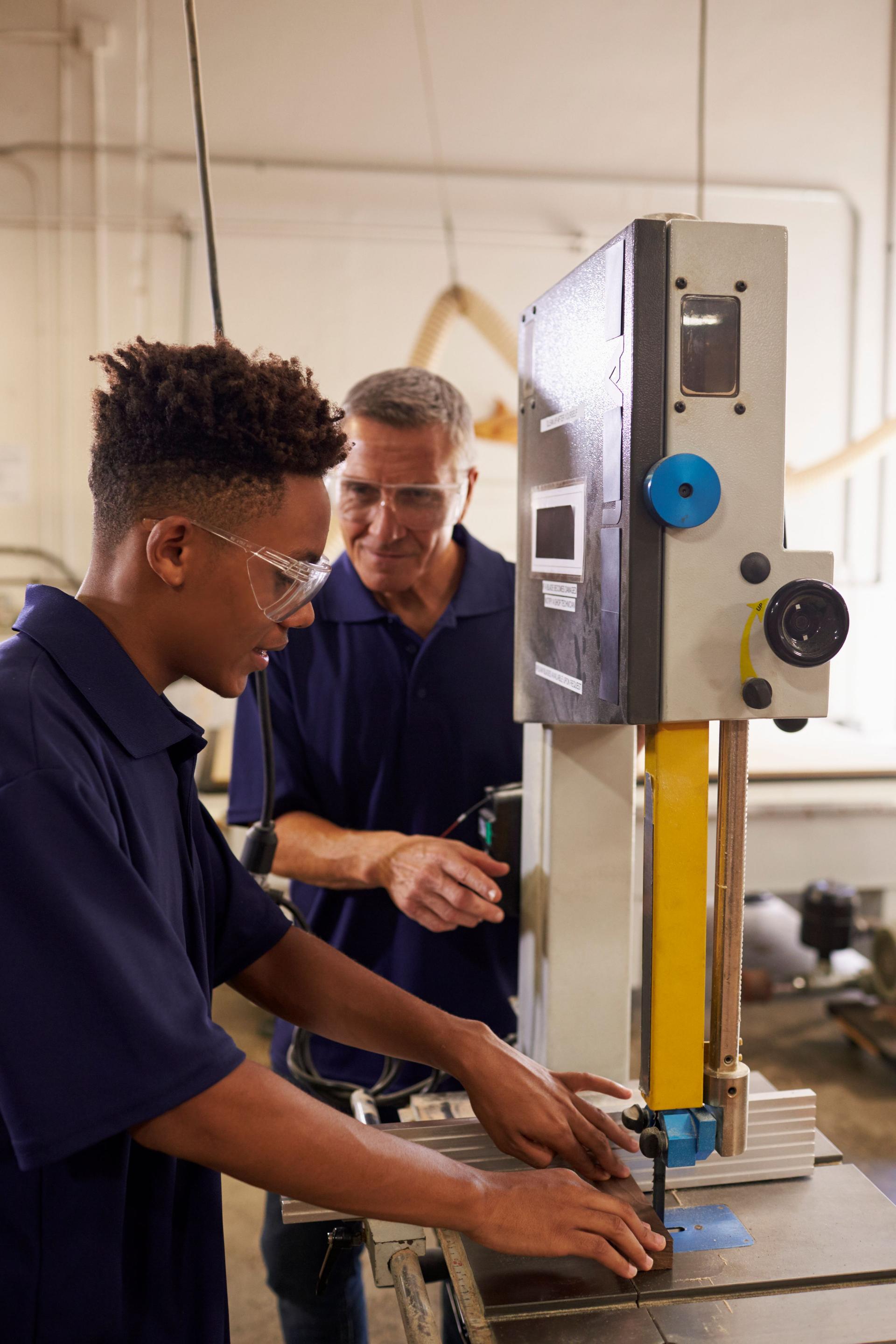 Carpenter Training Male Apprentice To Use Mechanized Saw